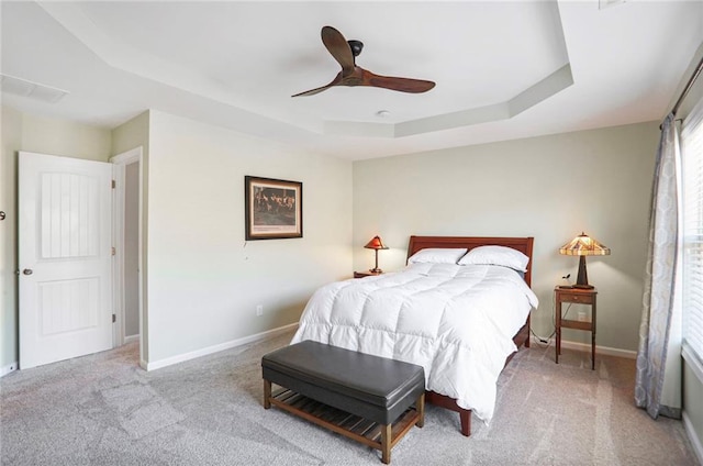 carpeted bedroom with a tray ceiling, baseboards, and ceiling fan