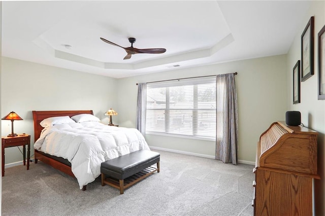 carpeted bedroom with visible vents, a ceiling fan, a raised ceiling, and baseboards