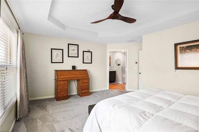 bedroom featuring ensuite bath, a raised ceiling, carpet, and baseboards