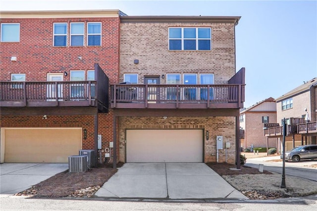 back of house featuring concrete driveway, central air condition unit, an attached garage, and brick siding