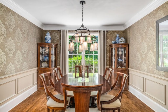 dining room with a chandelier, wood finished floors, a wainscoted wall, wallpapered walls, and a decorative wall