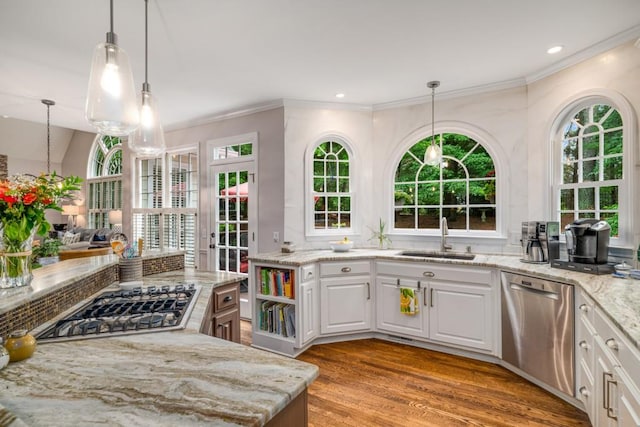 kitchen featuring stainless steel appliances, a sink, light stone counters, crown molding, and light wood finished floors