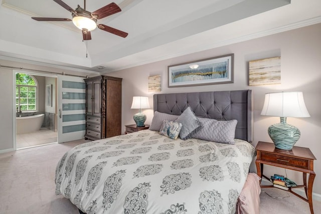 bedroom featuring a raised ceiling, light carpet, crown molding, ensuite bathroom, and baseboards