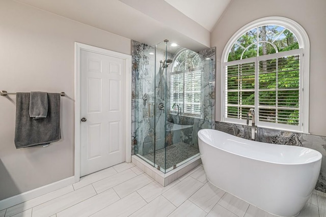 full bath with a marble finish shower, a freestanding bath, vaulted ceiling, and tile patterned floors