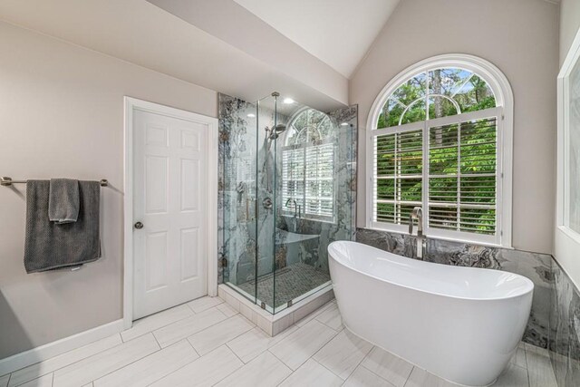 full bath with a shower stall, a freestanding tub, and vaulted ceiling