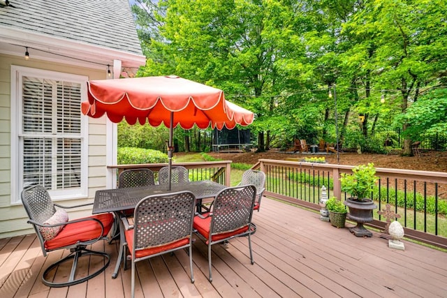 wooden deck featuring outdoor dining area and a trampoline