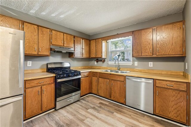 kitchen with a healthy amount of sunlight, sink, stainless steel appliances, and a textured ceiling