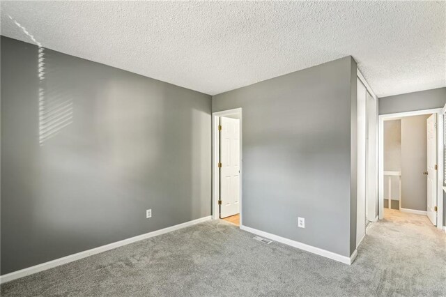 carpeted empty room featuring a textured ceiling