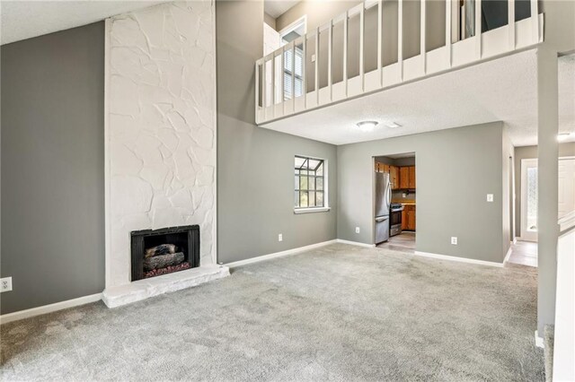 unfurnished living room with a fireplace, carpet floors, a textured ceiling, and vaulted ceiling