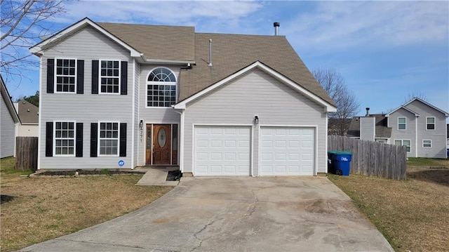 traditional home with a front yard, concrete driveway, an attached garage, and fence