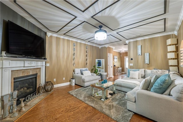 living room with crown molding, wood walls, wood finished floors, baseboards, and a tiled fireplace