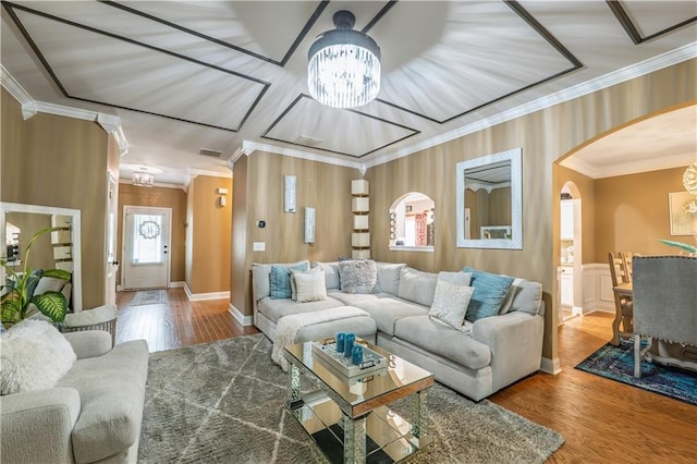 living room featuring arched walkways, wood finished floors, a chandelier, and ornamental molding