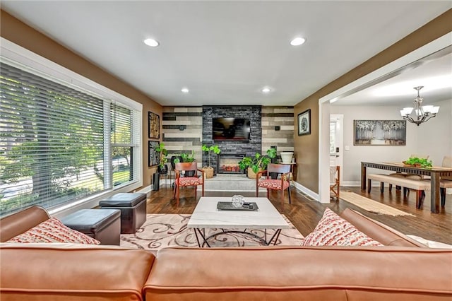 living area with a chandelier, recessed lighting, an accent wall, a fireplace, and wood finished floors