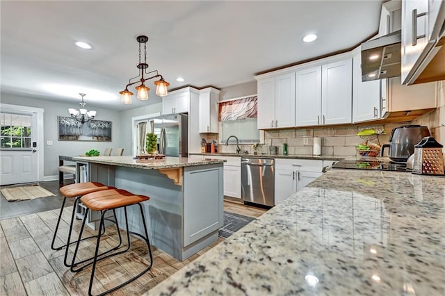 kitchen featuring a center island, stainless steel appliances, decorative backsplash, white cabinets, and a kitchen bar