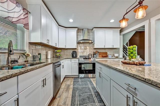 kitchen with dark wood-style floors, a sink, stainless steel appliances, wall chimney range hood, and backsplash