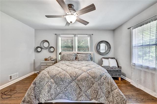 bedroom with dark wood-style floors, ceiling fan, visible vents, and baseboards