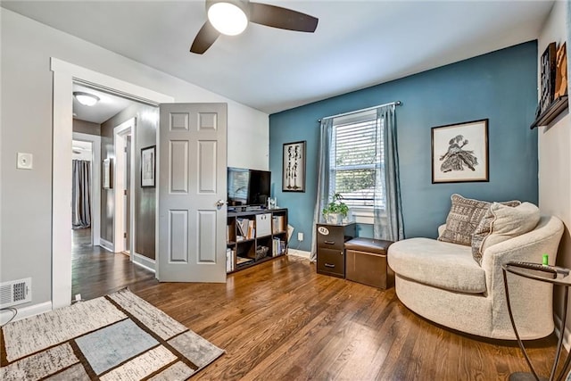 sitting room with ceiling fan, wood finished floors, visible vents, and baseboards