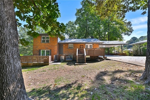 back of property with driveway, a deck, a carport, and brick siding