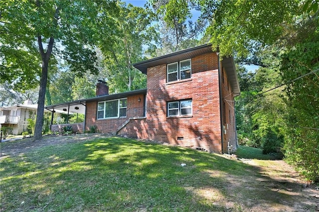 view of front of house with a chimney, an attached carport, crawl space, a front lawn, and brick siding