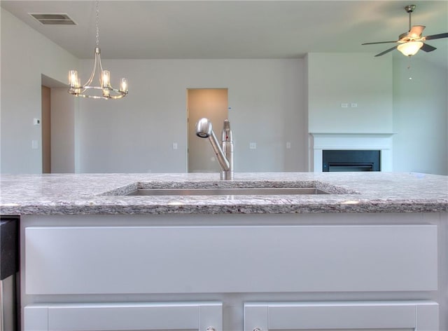 111 Ginger Trl, Homer, GA 30547 - kitchen with a sink, light stone counters, a ceiling fan, and a chandelier
