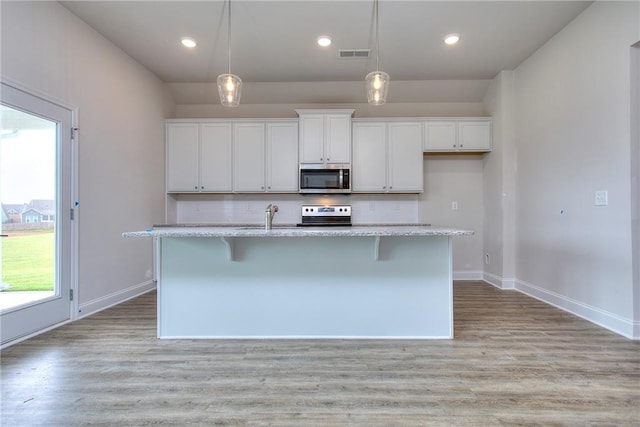 111 Ginger Trl, Homer, GA 30547 - kitchen with stainless steel microwave, range, white cabinets, a center island with sink, and recessed lighting