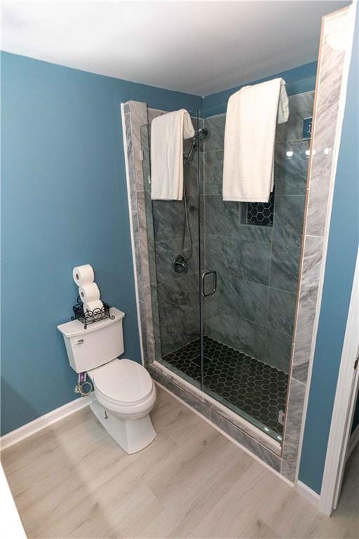 bathroom with hardwood / wood-style flooring, toilet, and a shower with door