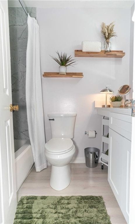 bathroom with shower / tub combo with curtain, wood-type flooring, and toilet