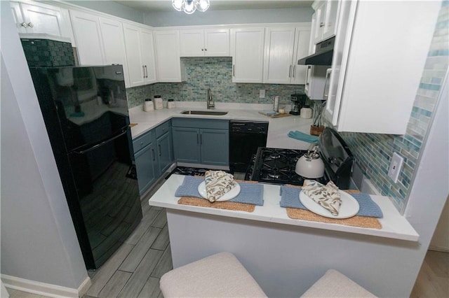 kitchen with gray cabinetry, white cabinetry, sink, a kitchen bar, and black appliances