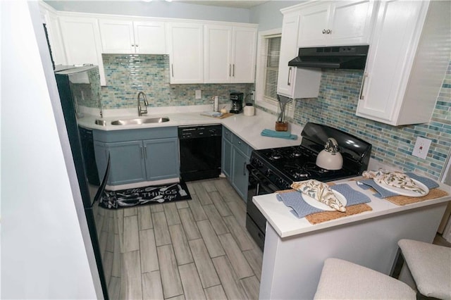 kitchen featuring a breakfast bar, black appliances, white cabinets, tasteful backsplash, and light hardwood / wood-style floors