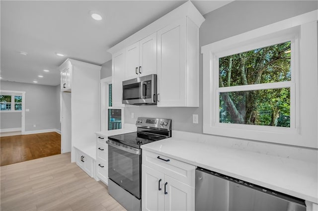 kitchen with white cabinets, appliances with stainless steel finishes, and a wealth of natural light