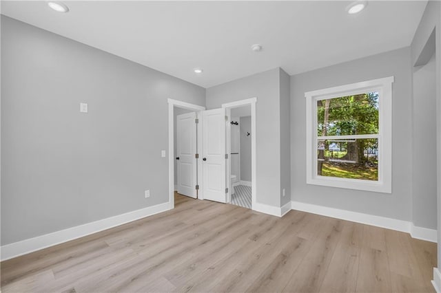 unfurnished bedroom featuring light wood-type flooring and ensuite bathroom