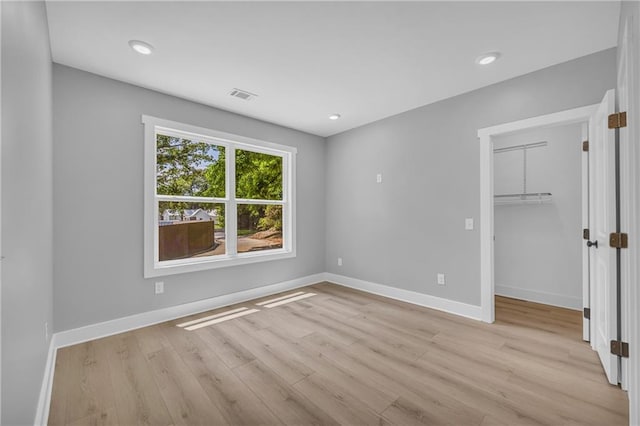 unfurnished bedroom featuring light hardwood / wood-style floors, a spacious closet, and a closet