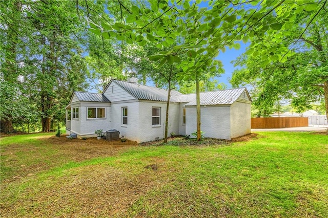 rear view of property featuring cooling unit and a lawn