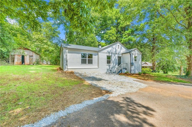 view of front of house featuring a storage unit and a front lawn