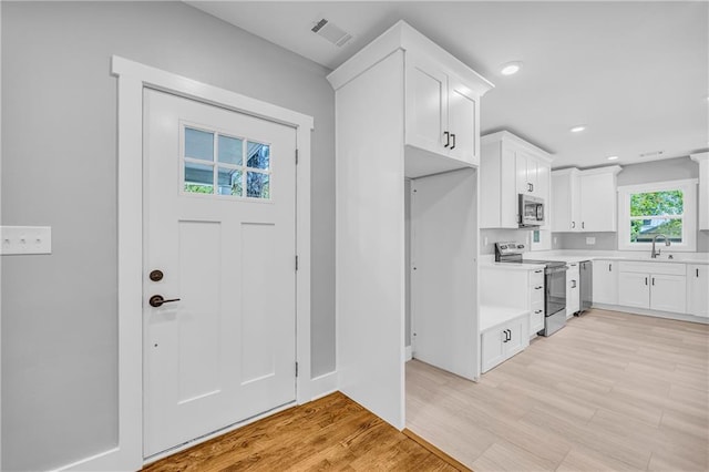 kitchen featuring sink, white cabinetry, light wood-type flooring, and appliances with stainless steel finishes