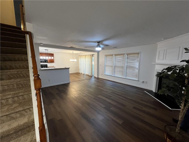 3613 Tinsley Way SW, Atlanta, GA 30331 - unfurnished living room with a chandelier, ceiling fan, dark wood-style flooring, stairs, and a fireplace with raised hearth