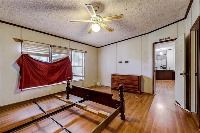 bedroom with ceiling fan, light wood-type flooring, and a textured ceiling