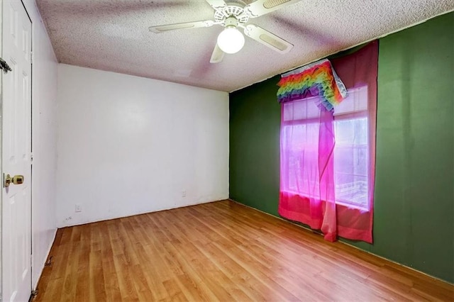 spare room featuring ceiling fan, light hardwood / wood-style floors, and a textured ceiling