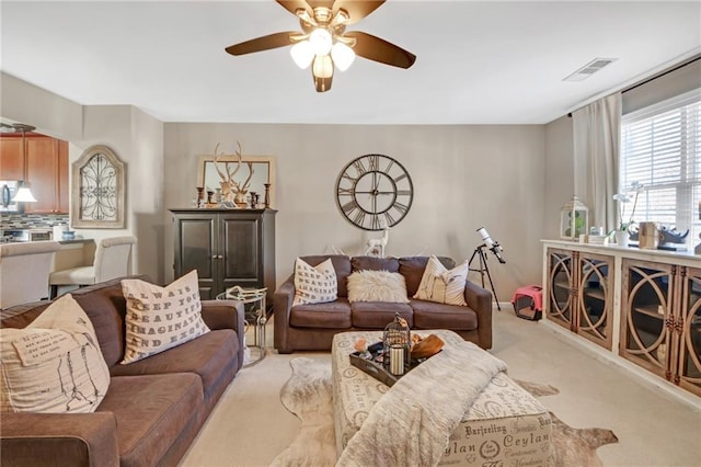 living area featuring light carpet, ceiling fan, and visible vents