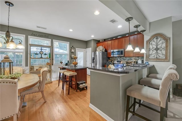 kitchen featuring appliances with stainless steel finishes, dark countertops, visible vents, and a breakfast bar area