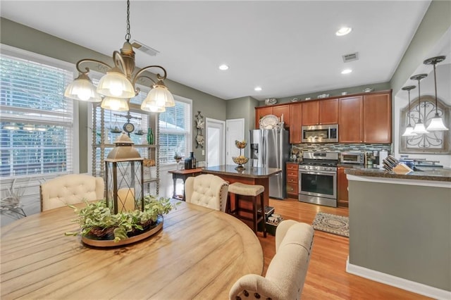 dining space featuring light wood-style flooring, recessed lighting, visible vents, and an inviting chandelier