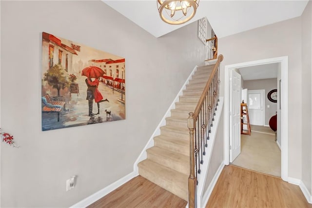 stairway featuring a chandelier, wood finished floors, and baseboards