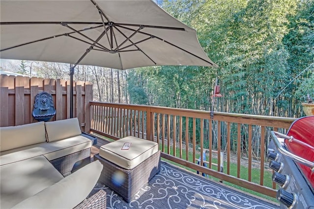 wooden deck featuring area for grilling, a wooded view, an outdoor living space, and fence