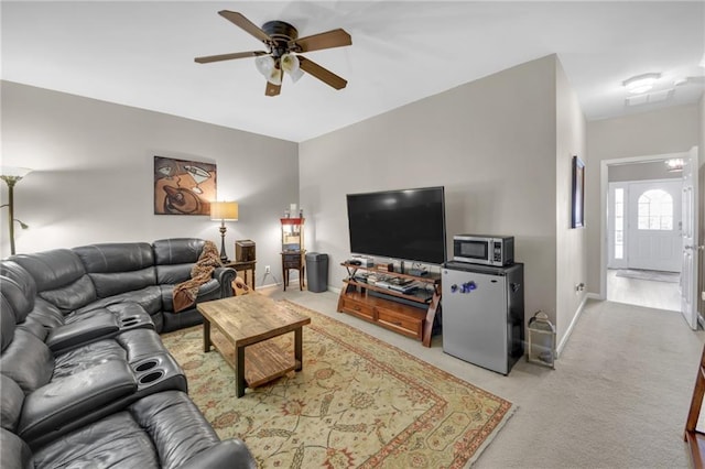 living room featuring baseboards, a ceiling fan, and light colored carpet