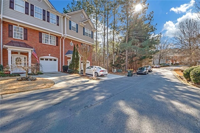 view of front of property featuring driveway, an attached garage, a residential view, and brick siding