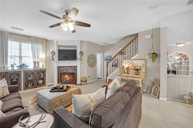 carpeted living area featuring stairway, a lit fireplace, visible vents, and baseboards