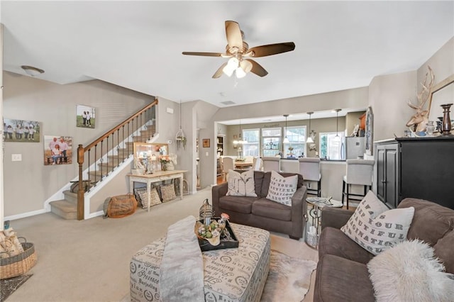 carpeted living room featuring ceiling fan, baseboards, and stairs