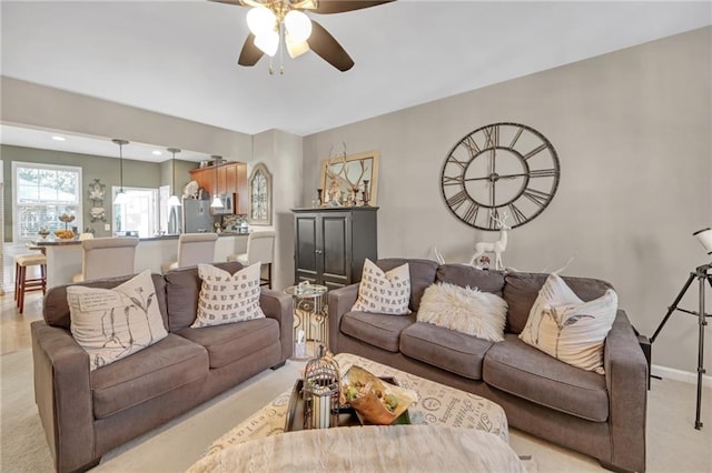 living area featuring ceiling fan and baseboards