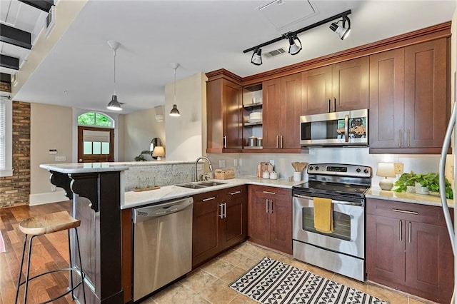 kitchen with visible vents, appliances with stainless steel finishes, light stone countertops, a sink, and a peninsula