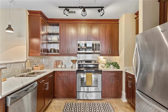 kitchen with light stone countertops, a sink, appliances with stainless steel finishes, light tile patterned floors, and decorative light fixtures